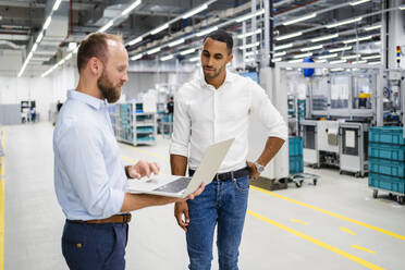 Businessman with laptop and colleague in a factory - DIGF20598