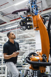 Techniker bei der Untersuchung eines Industrieroboters in einer Fabrik - DIGF20616