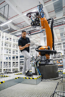Techniker mit digitalem Tablet an einem Industrieroboter in einer Fabrik - DIGF20618