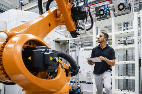 Technician examining industrial robot in a factory - DIGF20621