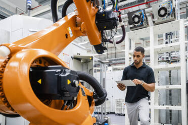 Techniker mit digitalem Tablet an einem Industrieroboter in einer Fabrik - DIGF20622
