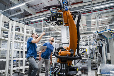 Zwei Techniker untersuchen einen Industrieroboter in einer Fabrik - DIGF20625