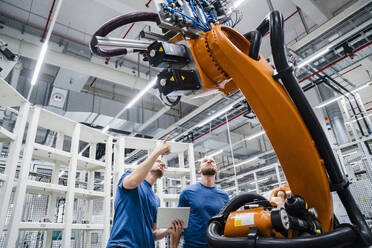 Two technicians examining industrial robot in a factory - DIGF20626