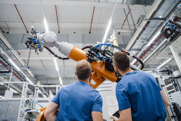 Zwei Techniker untersuchen einen Industrieroboter in einer Fabrik - DIGF20627