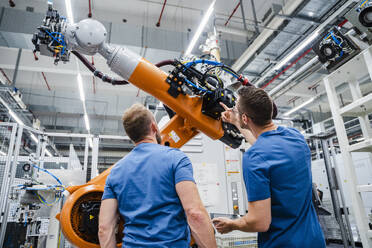 Zwei Techniker untersuchen einen Industrieroboter in einer Fabrik - DIGF20628