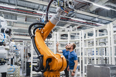 Two technicians examining industrial robot in a factory - DIGF20629