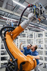 Two technicians examining industrial robot in a factory - DIGF20630