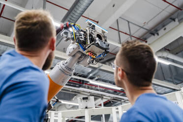 Zwei Techniker untersuchen einen Industrieroboter in einer Fabrik - DIGF20632