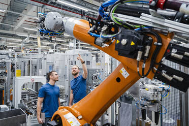 Two technicians examining industrial robot in a factory - DIGF20633