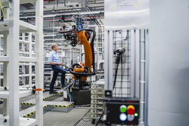 Businessman examining industrial robot in a factory - DIGF20641