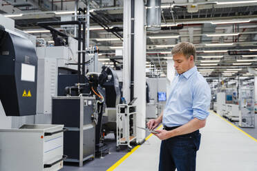 Businessman using digital tablet on shop floor in a factory - DIGF20648