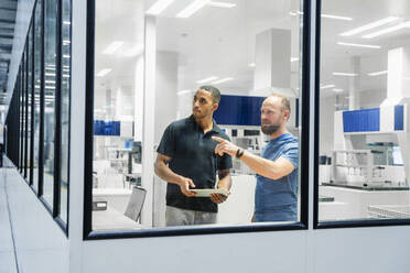 Zwei Kollegen mit digitalem Tablet bei einer Besprechung in einer Fabrik - DIGF20660