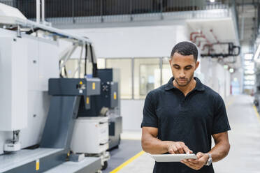 Technician using digital tablet on shop floor in a factory - DIGF20672