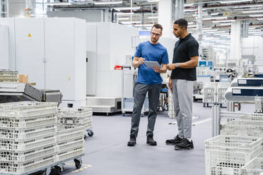 Zwei Kollegen mit digitalem Tablet im Gespräch in einer Fabrik - DIGF20694