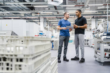 Two colleagues with digital tablet talking in a factory - DIGF20698