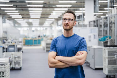 Employee standing in a factory with arms crossed - DIGF20715