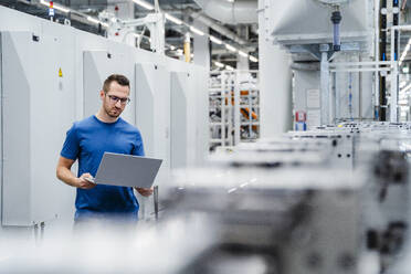 Technician using laptop on shop floor in a factory - DIGF20716