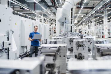 Technician using laptop on shop floor in a factory - DIGF20717