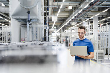 Technician using laptop on shop floor in a factory - DIGF20723