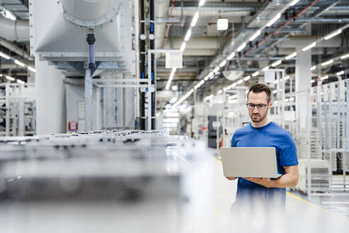 Techniker mit Laptop in einer Fabrikhalle - DIGF20723