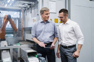 Two businessmen with digital tablet having a meeting in a factory - DIGF20738