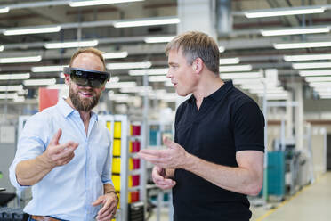 Techniker mit Augmented-Reality-Brille in einer Fabrik interagiert mit einem Kollegen - DIGF20773