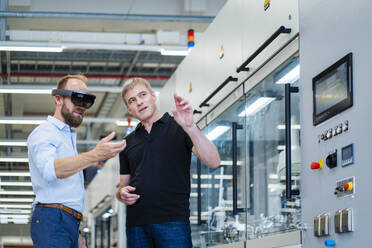 Techniker mit Augmented-Reality-Brille in einer Fabrik interagiert mit einem Kollegen - DIGF20774