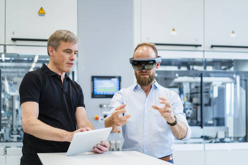 Techniker mit Augmented-Reality-Brille in einer Fabrik interagiert mit einem Kollegen - DIGF20777