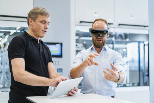 Techniker mit Augmented-Reality-Brille in einer Fabrik interagiert mit einem Kollegen - DIGF20778