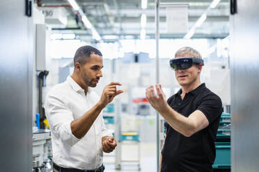 Techniker mit Augmented-Reality-Brille in einer Fabrik interagiert mit einem Kollegen - DIGF20782