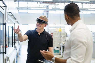 Techniker mit Augmented-Reality-Brille in einer Fabrik interagiert mit einem Kollegen - DIGF20784