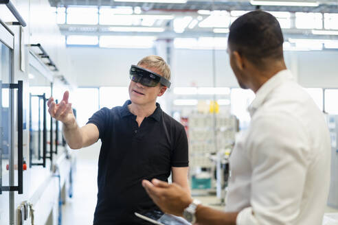Techniker mit Augmented-Reality-Brille in einer Fabrik interagiert mit einem Kollegen - DIGF20784