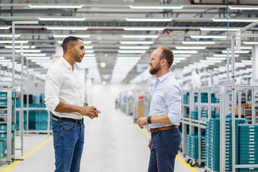 Two businessmen standing and talking in a factory - DIGF20787