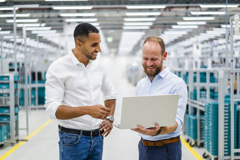 Zwei Geschäftsleute mit Laptop bei einer Besprechung in einer Fabrik - DIGF20791