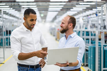 Two businessmen with laptop having a meeting in a factory - DIGF20792