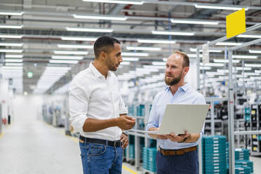 Zwei Geschäftsleute mit Laptop bei einer Besprechung in einer Fabrik - DIGF20794