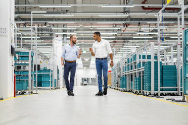 Two businessmen walking and talking in a factory - DIGF20799