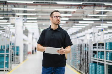 Techniker mit digitalem Tablet in einer Fabrik, der sich umschaut - DIGF20812