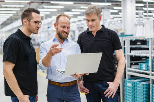 Geschäftsmann teilt Laptop mit Angestellten in einer Fabrik - DIGF20814