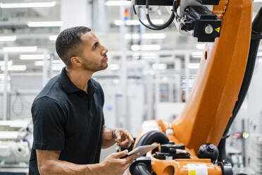 Technician examining industrial robot in a factory - DIGF20827
