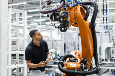 Technician examining industrial robot in a factory - DIGF20828