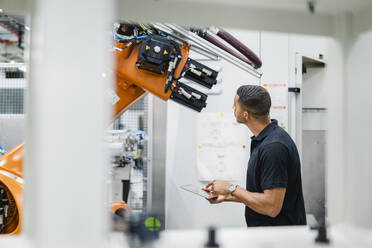 Techniker bei der Untersuchung eines Industrieroboters in einer Fabrik - DIGF20830
