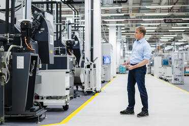 Businessman using digital tablet on shop floor in a factory - DIGF20834