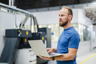 Technician using laptop on shop floor in a factory - DIGF20838