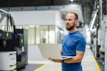 Techniker mit Laptop in einer Fabrikhalle - DIGF20839