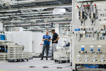 Two colleagues with digital tablet standing in a factory - DIGF20843