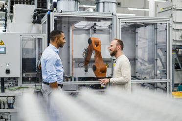 Employee and businessman talking at industrial robot in a factory - DIGF20850