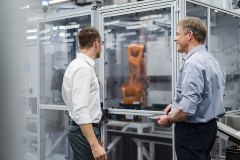 Two businessmen having a meeting at industrial robot in a factory - DIGF20851