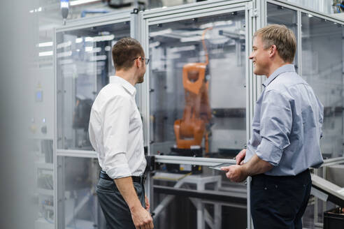Zwei Geschäftsleute bei einem Treffen an einem Industrieroboter in einer Fabrik - DIGF20851