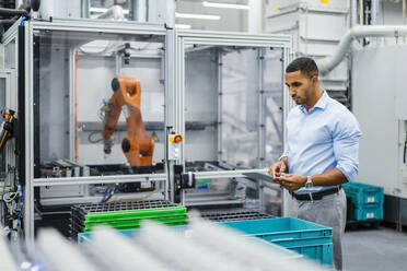 Businessman using digital tablet on shop floor in a factory - DIGF20857